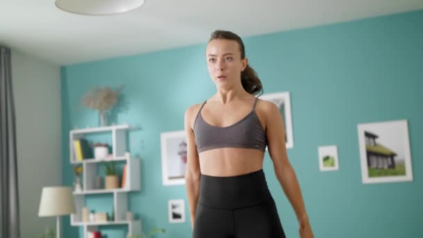 Hermosa mujer hace ejercicios de cardio por la mañana saltando en una habitación acogedora — Vídeo de stock