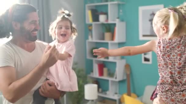 Mamá y papá están bailando con sus hijas en sus brazos en la sala de estar — Vídeos de Stock