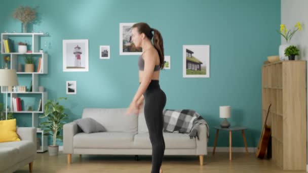 Hermosa mujer delgada hace ejercicios de cardio por la mañana saltando en casa — Vídeos de Stock