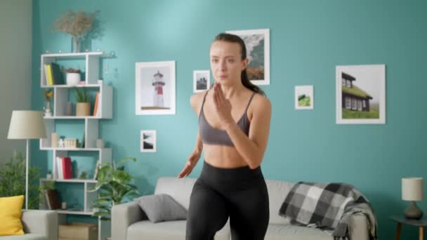 Piękna kobieta robi poranne ćwiczenia cardio uruchomione na miejscu w pokoju — Wideo stockowe