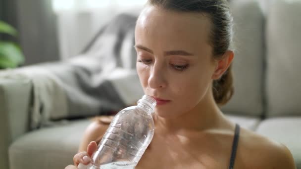 Frau trinkt Wasser nach Fitnessübungen zu Hause — Stockvideo