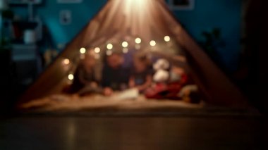 Baba kızları ile oturma odasında el yapımı bir wigwam bir kitap okuma