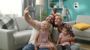 Evde yerde selfie aile fotoğrafı çeken kızları ile gülümseyen anne-babalar
