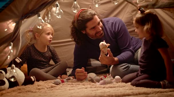 Papá con hijas juega con un cerdo de juguete en una tienda de campaña en casa . — Vídeo de stock