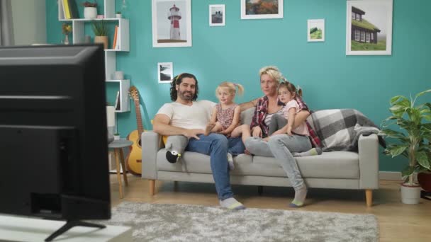 Щаслива сім'я дивитися телевізор вдома сидить на дивані — стокове відео