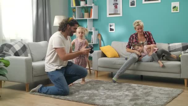 Hombre toma fotos de su familia en una cámara profesional en la sala de estar — Vídeos de Stock