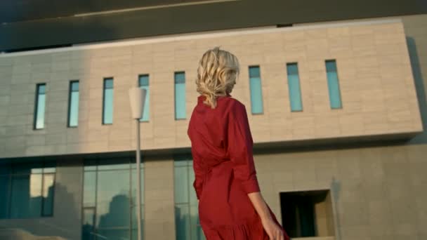 Mujer vestida de rojo con bolsas de compras caminando en una ciudad al atardecer. Movimiento lento — Vídeo de stock