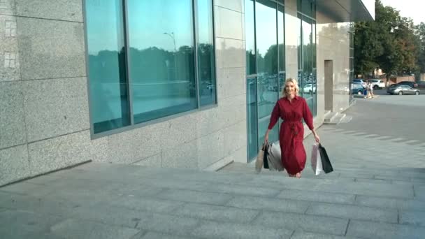 Торговая девушка с сумками прогуливаясь по городу и поднимаясь по лестнице — стоковое видео