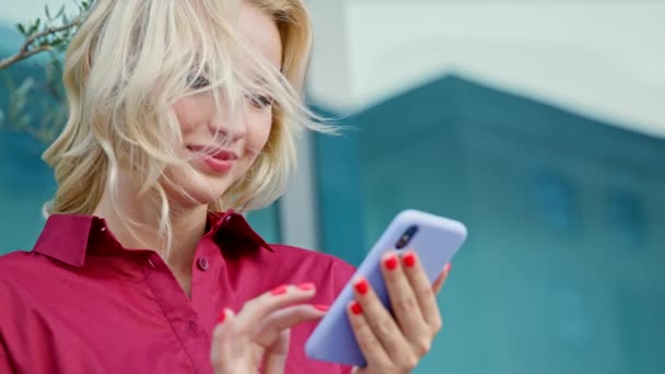 Junge schöne blonde Mädchen in einem roten Kleid benutzt das Telefon — Stockvideo