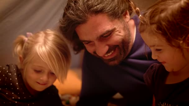 Vader met zijn dochters een boek lezen in een wigwam in de woonkamer — Stockvideo