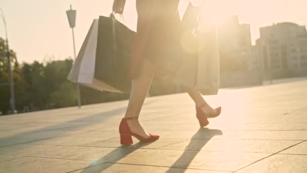 Junge Frau in rotem Kleid mit Einkaufstüten geht bei Sonnenuntergang auf die Straße — Stockvideo