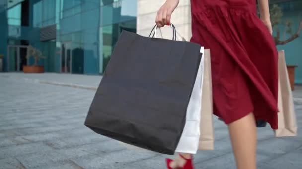 Mooie jonge Kaukasische vrouw in rode jurk wandelen langs het winkelcentrum — Stockvideo