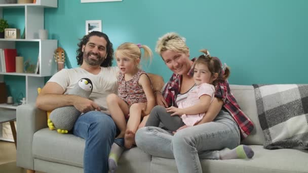 Mãe feliz, pai, filhas sentadas no sofá na sala de estar e assistindo TV — Vídeo de Stock