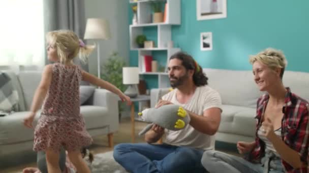 Чарівна маленька дівчинка танцює з татом і мамою у вітальні — стокове відео