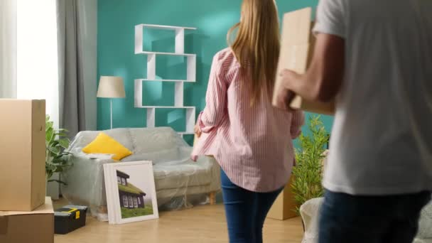 Um jovem casal traz caixas para um novo apartamento e dá um alto cinco — Vídeo de Stock