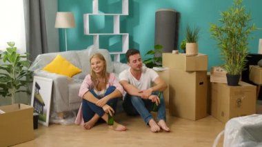 Genç adam ve kadın yeni bir daireye taşınmayı ve bira içmeyi kutluyor