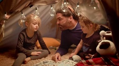 Babam akşamları evde ki oyuncak çadırında kızlarına kitap okur.