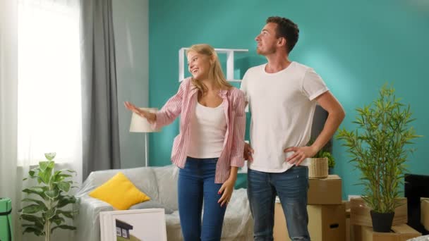Una pareja se está abrazando en su nuevo apartamento con felicidad . — Vídeo de stock