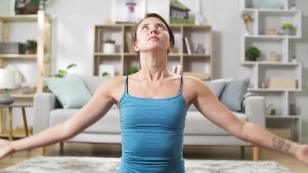 Guapa yogi femenina haciendo namaste en su sala de estar — Vídeos de Stock