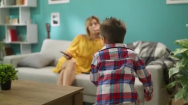 Anne ile küçük oğlu oturma odasında kanepede bir akıllı telefon üzerinde bir oyun oynar