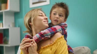 Küçük oğlu kanepede evde sıkıca anne kucaklar