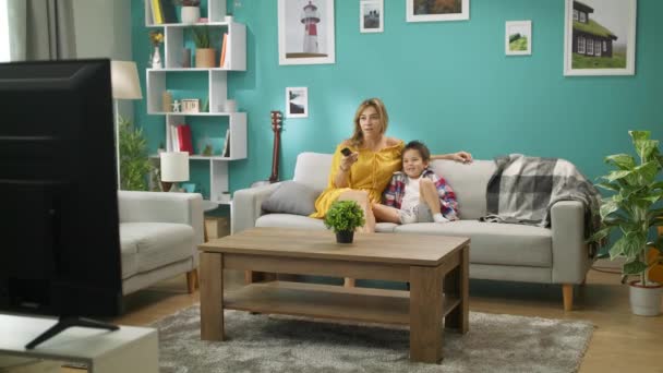 Mamá e hijo viendo dibujos animados en la televisión mientras están sentados en un sofá en la sala de estar — Vídeos de Stock