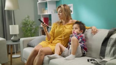 Anne ve oğlu gün bir kanepede otururken Tv'de çizgi film izlerken