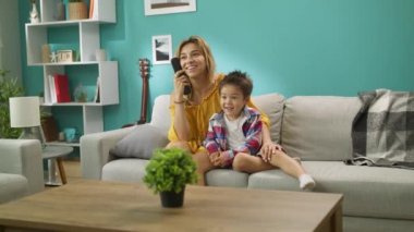 Mutlu çocuk kanepede evde sevgi dolu anne ile Tv izliyor