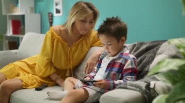 Anne ile Oğlu oturma odasında kanepede bir akıllı telefon üzerinde bir oyun oynar