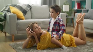 Oğlu ve anne yerde yatan çizgi film izliyor