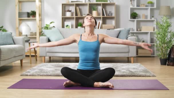 Pretty woman in lotus position doing namaste in living room — Stock Video