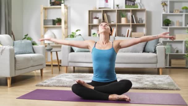 Mujer yogui sentada en el suelo en la sala de estar en loto con los dedos en Jnana mudra — Vídeos de Stock