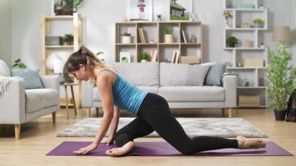 Bella donna yoga allunga le gambe, si piega e si estende a casa — Video Stock