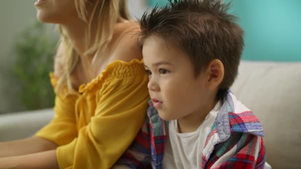 Niño está viendo la televisión con la madre cariñosa en casa en el sofá — Vídeo de stock