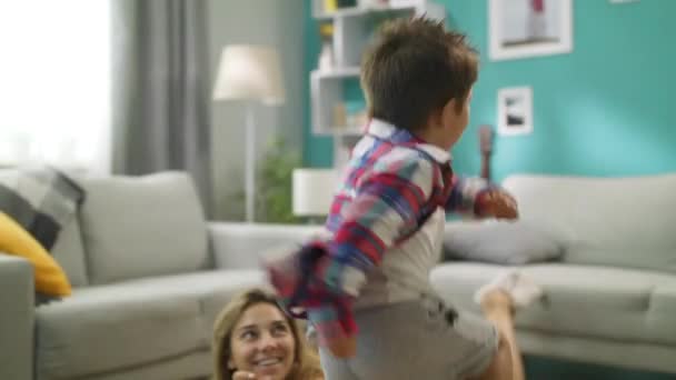 Mamma och son tittar på TV, son sitter på mammor tillbaka — Stockvideo