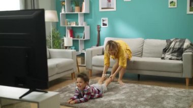 Annem yerde yatarken televizyon izleyen bir oğlu mukaveyle çekiyor.