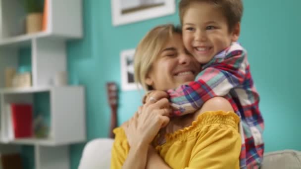 小さな男の子はソファの上で自宅でしっかりとお母さんを抱きしめる — ストック動画