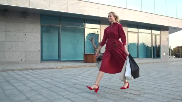 Jeune fille marcher près d'un centre commercial avec plein d'achats sacs à provisions — Video