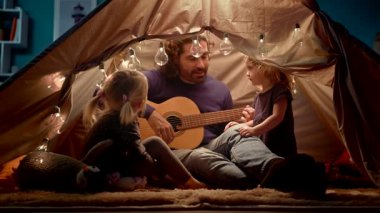 Babam gitar çalıyor ve çocuk çadırında şarkı lar söyledi.