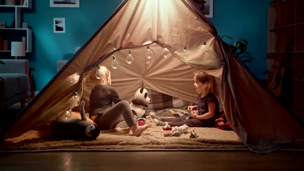 İki kız kardeş odada bir oyuncak çadırda oyuncaklar ile oynamak — Stok video