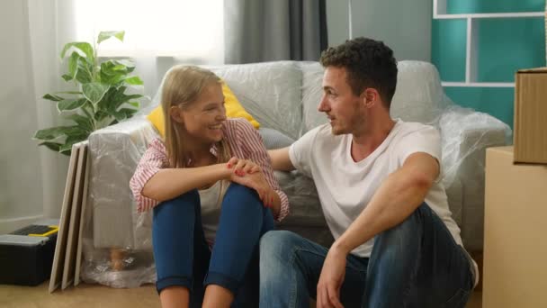 Couple parlant et riant assis par terre dans un nouvel appartement — Video
