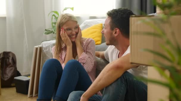 Pareja hablando y riendo mientras se sienta en el suelo en un nuevo apartamento — Vídeos de Stock