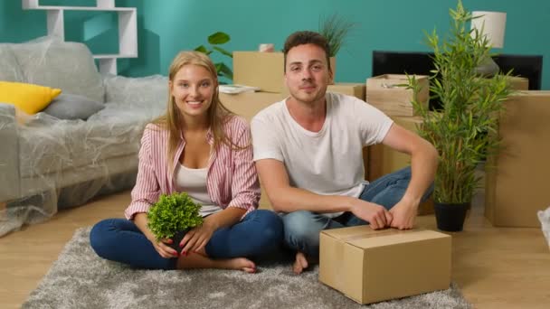 Portret van een jong stel in een nieuw appartement zittend op de vloer — Stockvideo