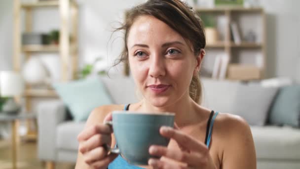 Chica después de entrenar bebe agua de una taza mientras está sentado en el suelo — Vídeos de Stock