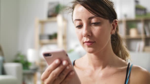 Mulher usa o telefone enquanto relaxa depois de fazer ioga — Vídeo de Stock