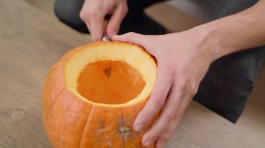 Genç adam Jack Lantern 'in dişlerini bıçakla kesiyor.