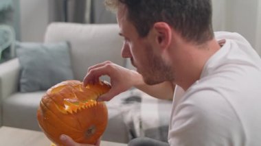 Genç adam evinde bıçakla Jack Lantern 'in dişlerini kesiyor.