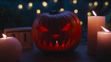 Ahşap masa üzerinde mumları olan Cadılar Bayramı balkabakları.