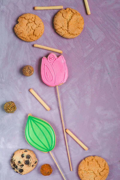 Gingerbread on a stick in the form of tulips on a lilac background. Homemade holiday pastries — Stock Photo, Image