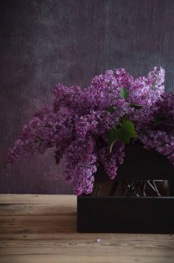 koyu ahşap bir arka plan üzerinde bir sepet içinde leylak buket